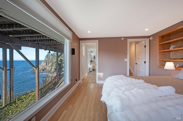 bedroom with a water view, light wood-style flooring, baseboards, and recessed lighting