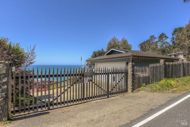 view of gate featuring a water view and fence