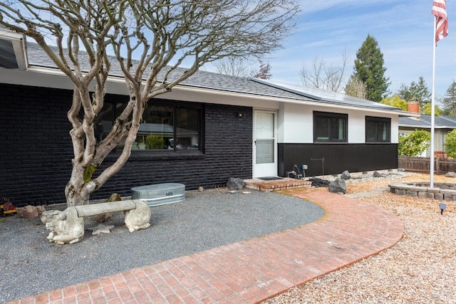 ranch-style house with roof with shingles and brick siding