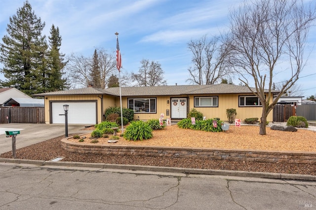 ranch-style home featuring driveway, an attached garage, and fence