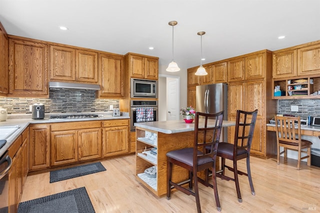 kitchen featuring light countertops, open shelves, stainless steel appliances, under cabinet range hood, and brown cabinetry