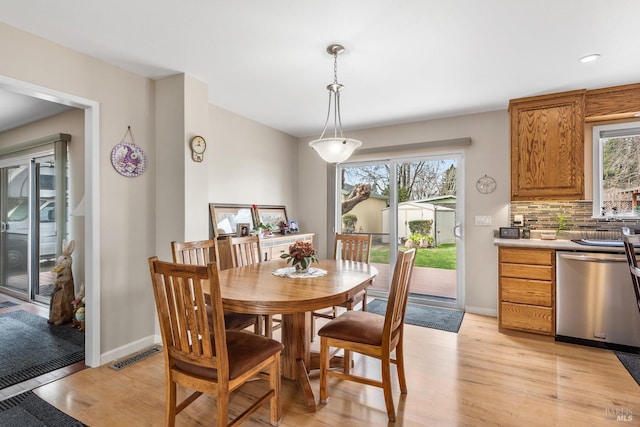 dining space with a wealth of natural light, visible vents, and light wood finished floors