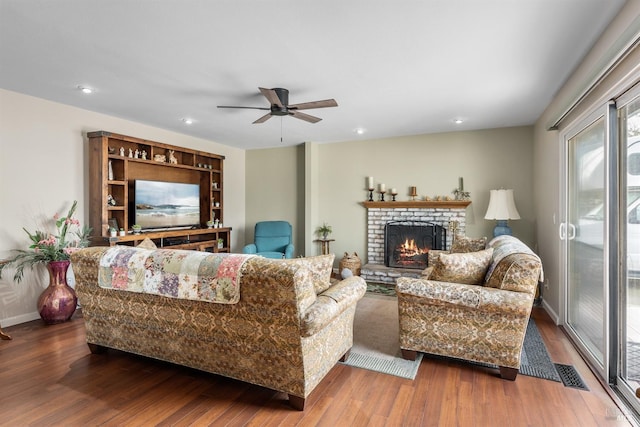 living room with a fireplace, wood finished floors, baseboards, visible vents, and ceiling fan