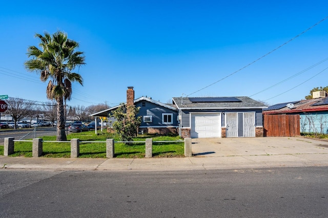 view of front of house featuring fence private yard, roof mounted solar panels, concrete driveway, and brick siding