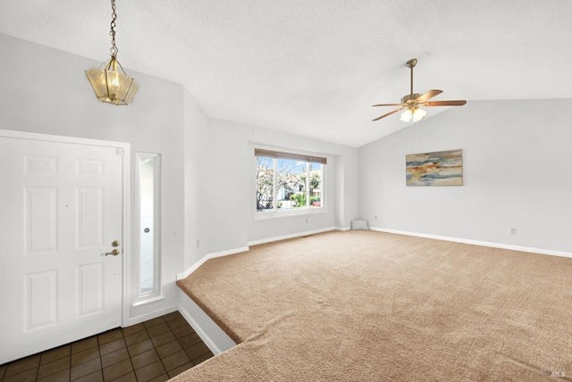 entryway featuring ceiling fan, lofted ceiling, dark carpet, and a textured ceiling