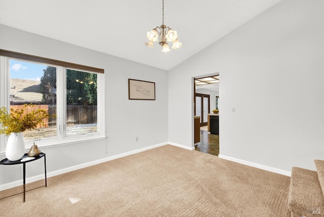 spare room featuring lofted ceiling, carpet floors, and a chandelier