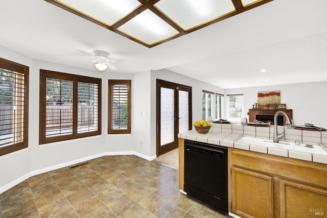 kitchen featuring a wealth of natural light, sink, black dishwasher, and tile counters