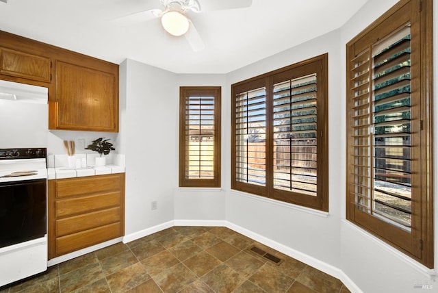 kitchen with ceiling fan, extractor fan, electric range oven, and a wealth of natural light