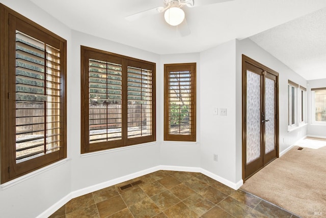 foyer with dark colored carpet, ceiling fan, and french doors