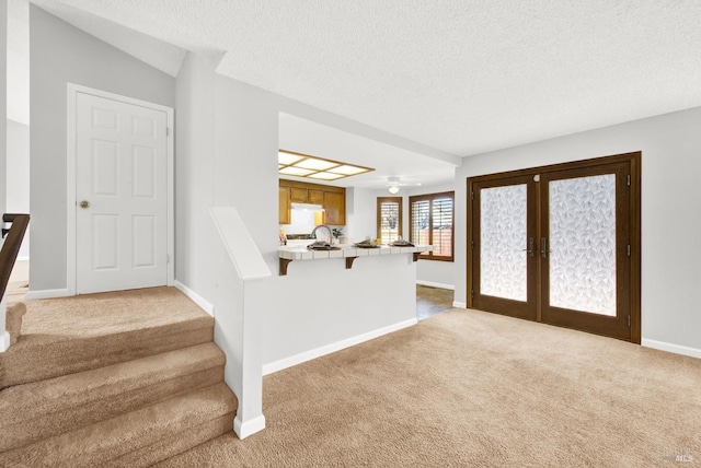 carpeted entrance foyer with a textured ceiling and french doors