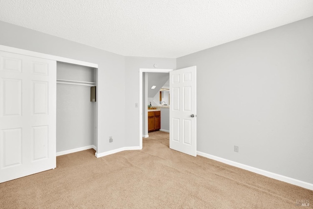 unfurnished bedroom with light carpet, a textured ceiling, and a closet