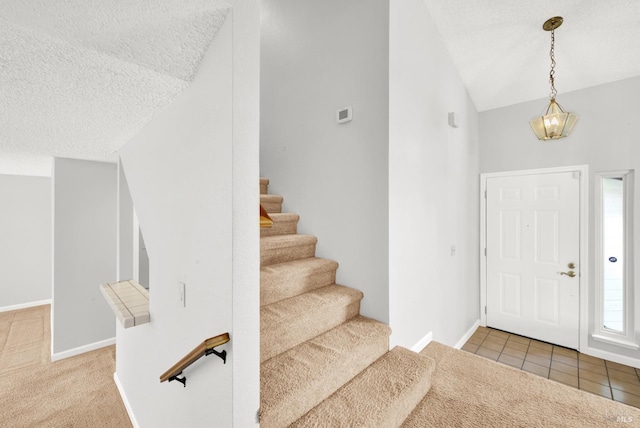 foyer with vaulted ceiling, carpet flooring, and a textured ceiling