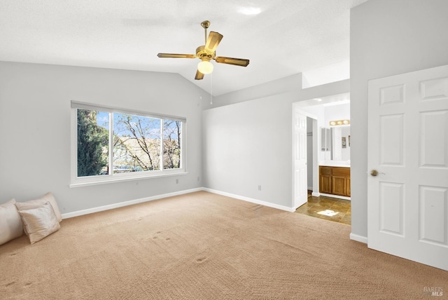 unfurnished bedroom featuring ceiling fan, lofted ceiling, connected bathroom, and light carpet