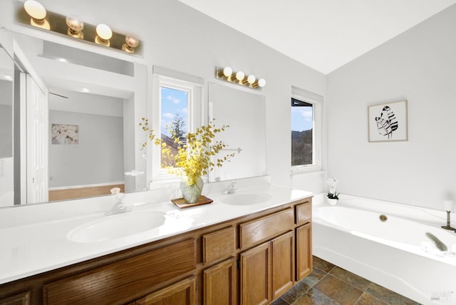 bathroom with vanity, a bath, and vaulted ceiling