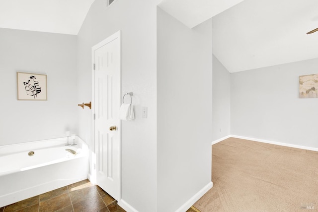 bathroom with a tub to relax in and vaulted ceiling