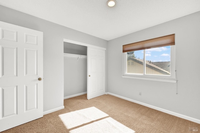 unfurnished bedroom featuring light colored carpet, a textured ceiling, and a closet