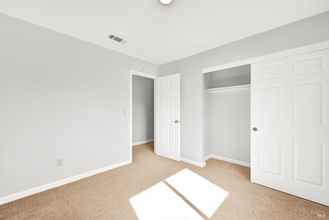 unfurnished bedroom with a closet and light carpet