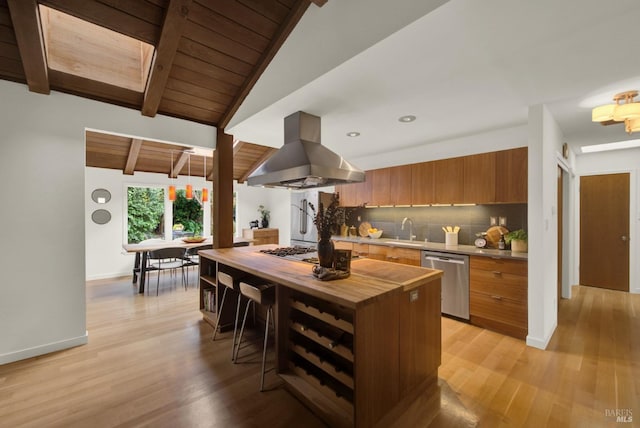 kitchen featuring stainless steel appliances, tasteful backsplash, island range hood, brown cabinets, and wood counters