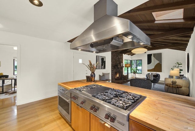 kitchen with wood counters, island range hood, open floor plan, and stainless steel appliances