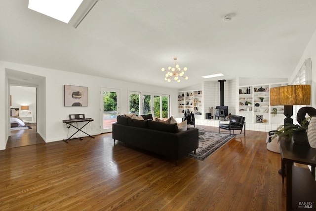living area featuring vaulted ceiling, wood finished floors, built in shelves, an inviting chandelier, and a wood stove