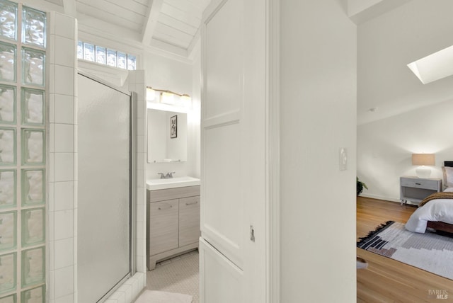 bathroom featuring lofted ceiling with skylight, a tile shower, ensuite bathroom, wood finished floors, and vanity