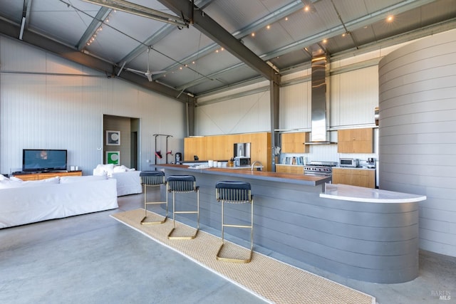 kitchen with sink, a breakfast bar, concrete flooring, high end stainless steel range, and kitchen peninsula