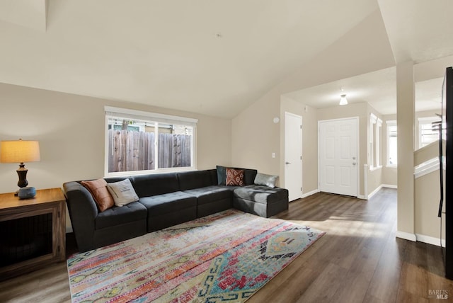 living room featuring dark wood-type flooring, vaulted ceiling, and a healthy amount of sunlight