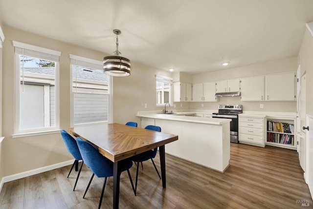 kitchen with sink, white cabinets, kitchen peninsula, stainless steel electric range, and hanging light fixtures