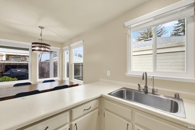 kitchen featuring sink, white cabinets, and pendant lighting