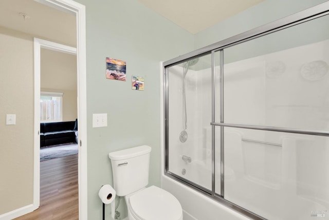 bathroom with toilet, hardwood / wood-style flooring, and bath / shower combo with glass door