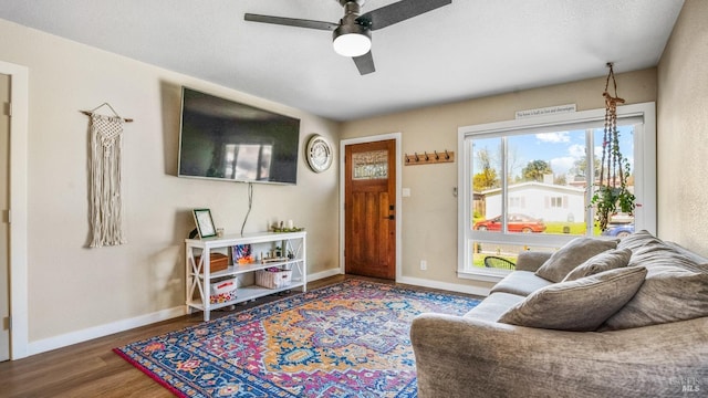 living room with a ceiling fan, baseboards, and wood finished floors