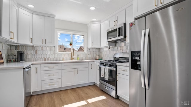 kitchen featuring light countertops, light wood-style flooring, appliances with stainless steel finishes, white cabinetry, and a sink