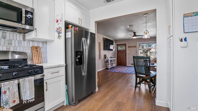 kitchen featuring light wood-style flooring, stainless steel appliances, visible vents, white cabinets, and tasteful backsplash