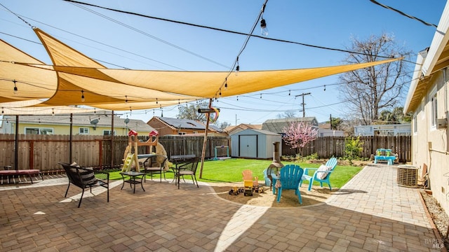 view of patio / terrace featuring an outdoor fire pit, a fenced backyard, central AC, an outdoor structure, and a shed