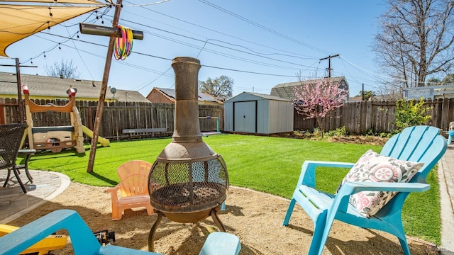 view of yard with a fenced backyard, a storage unit, a playground, and an outdoor structure