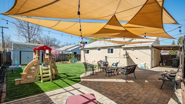 view of patio / terrace with a fenced backyard, a shed, a playground, and an outbuilding