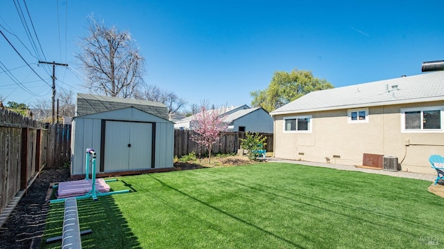 view of yard featuring a shed, central AC, a fenced backyard, and an outbuilding