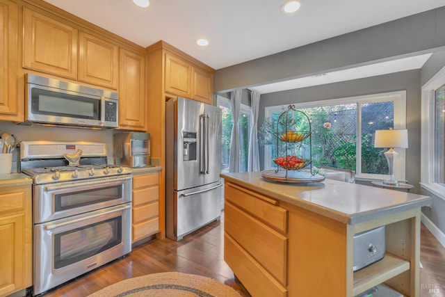 kitchen with dark wood-type flooring, appliances with stainless steel finishes, light brown cabinetry, and a kitchen island