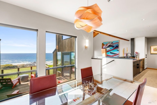 dining area with a water view, a beach view, light tile patterned flooring, and sink