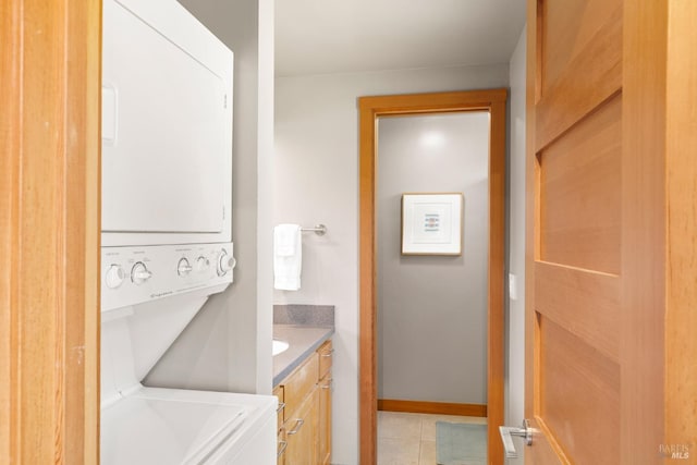 laundry room featuring light tile patterned flooring and stacked washer / dryer