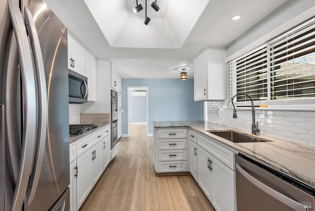 kitchen with a sink, light wood-style flooring, white cabinetry, and stainless steel appliances