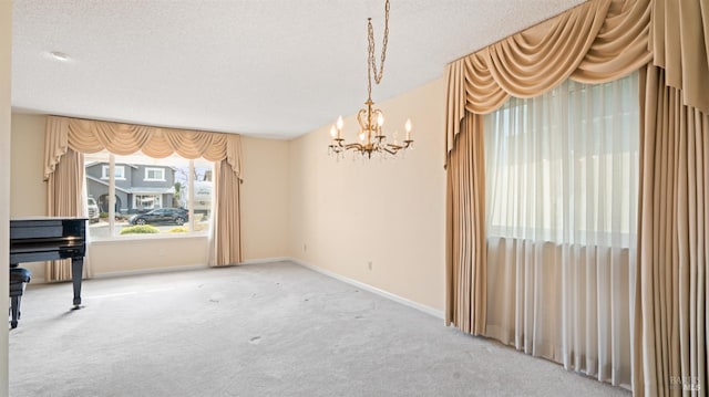 carpeted empty room featuring a notable chandelier, baseboards, and a textured ceiling