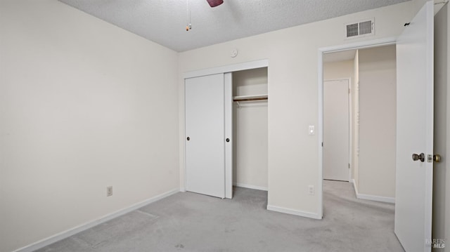 unfurnished bedroom with light carpet, a textured ceiling, a closet, and visible vents