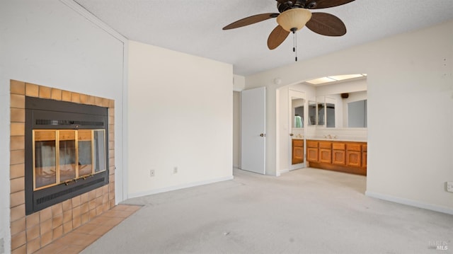 living area with light carpet, a fireplace, baseboards, and a textured ceiling
