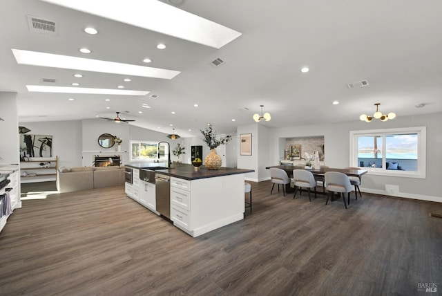 kitchen with lofted ceiling with skylight, sink, a breakfast bar area, a kitchen island with sink, and white cabinets