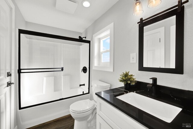 full bathroom featuring enclosed tub / shower combo, vanity, toilet, and wood-type flooring
