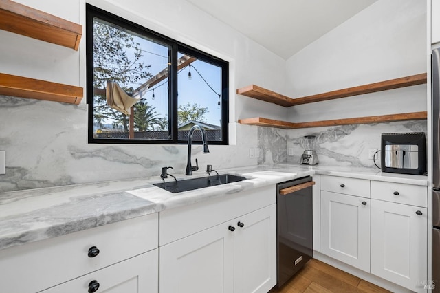 kitchen featuring black dishwasher, sink, white cabinets, and light stone counters