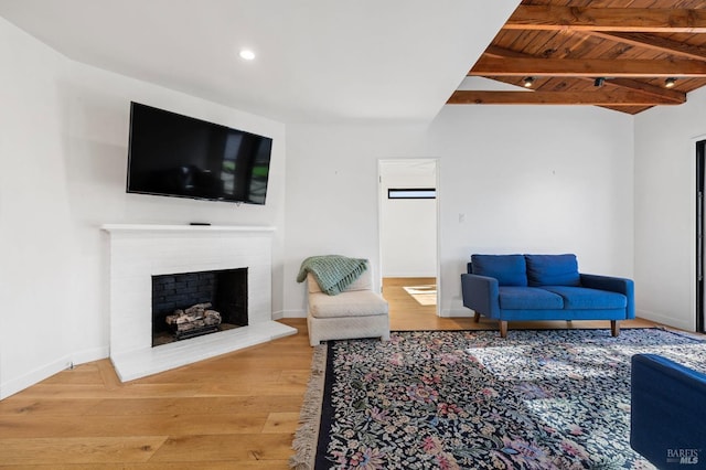 living room with hardwood / wood-style floors, wood ceiling, beamed ceiling, and a brick fireplace