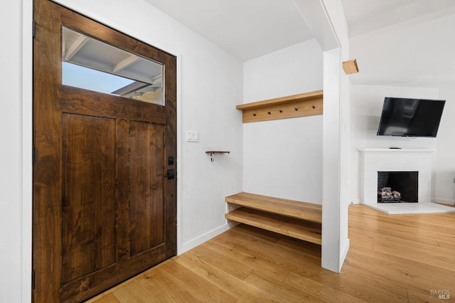 mudroom with a brick fireplace and light wood-type flooring