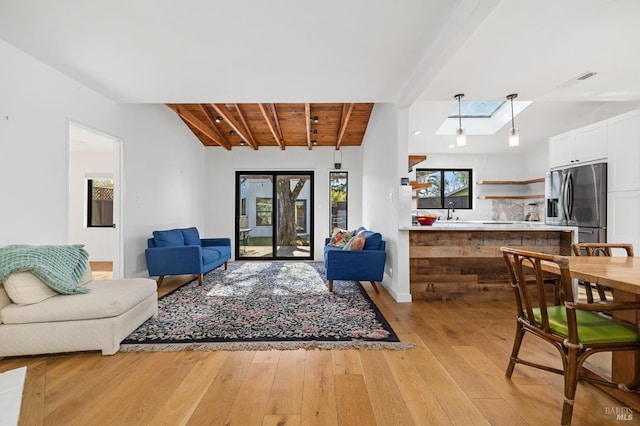 living room with light hardwood / wood-style flooring, wood ceiling, a skylight, and beamed ceiling